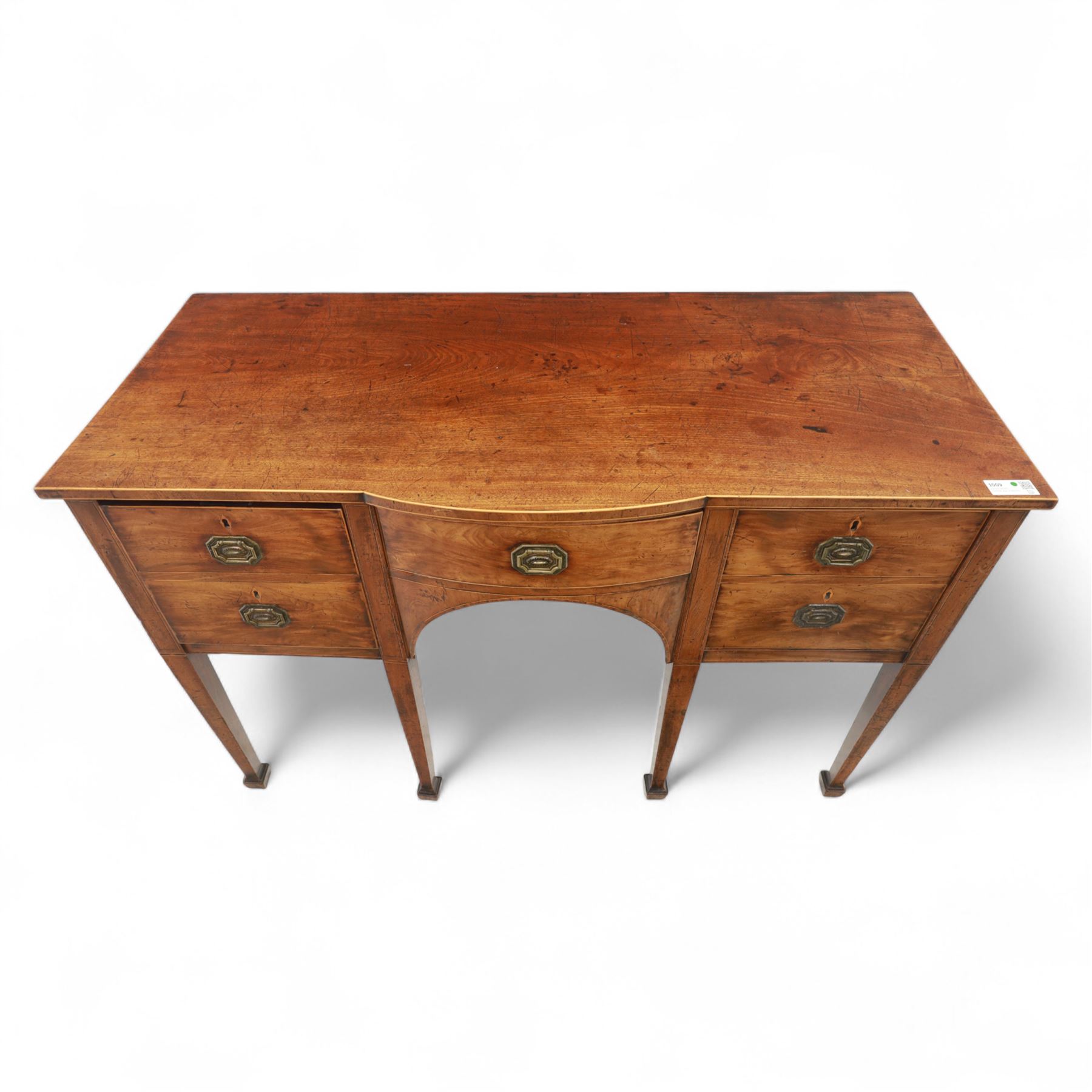 George III Sheraton-style mahogany sideboard, serpentine front fitted with central drawer and flanked by two deep drawers, raised on square tapered legs with spade feet 
