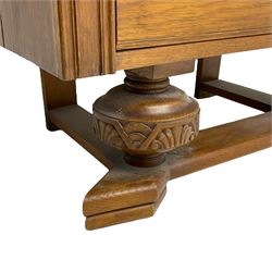 Early to mid-20th century oak bureau, the fall front enclosing fitted interior, three long drawers, on turned and carved baluster supports united by sledge platform 