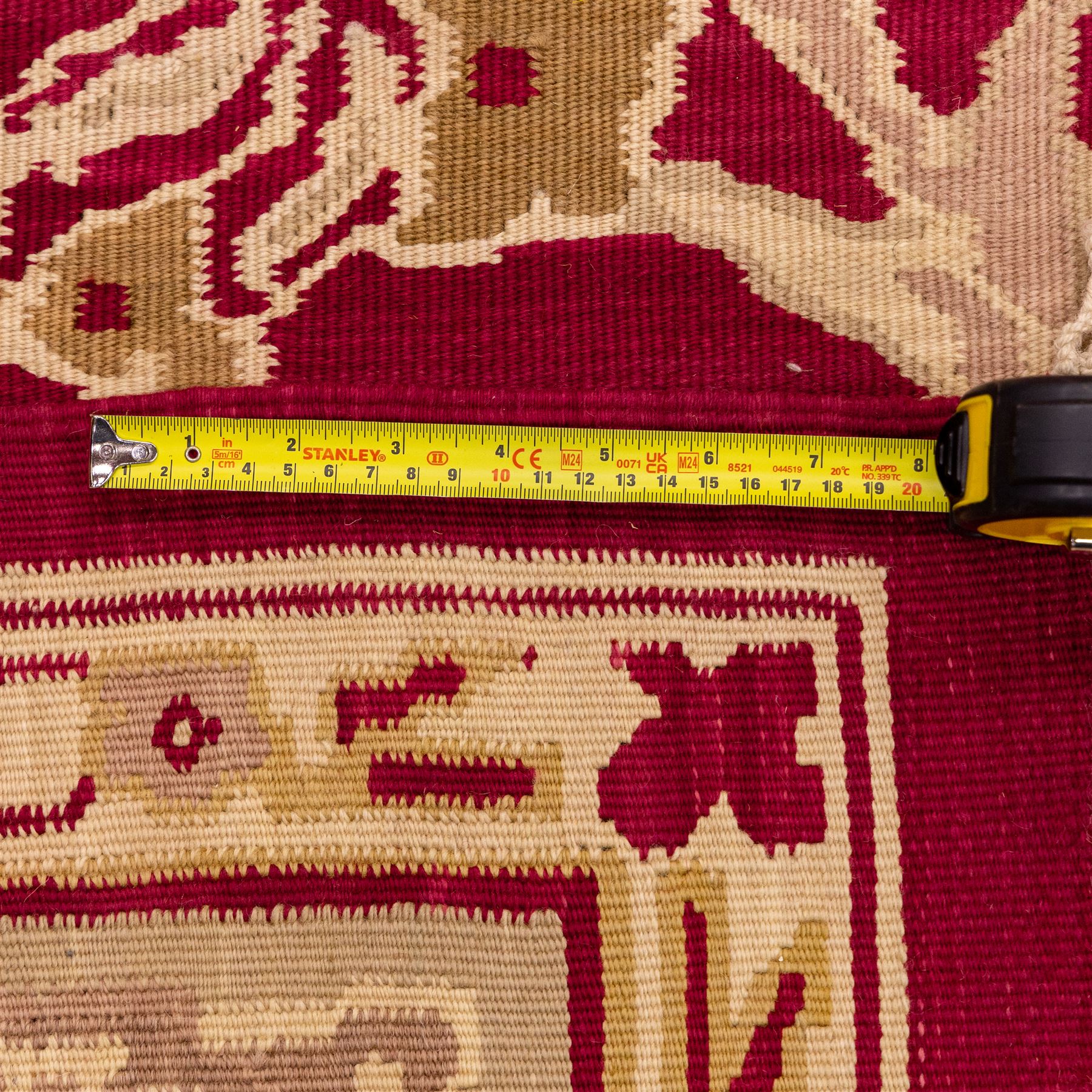 Large Persian Savonnerie-inspired style flatweave kilim, crimson field with central stylized palmette medallion with bold scrolling vinery and angular floral motifs between multiple guard stripes, rendered in tones of soft cream, pale sage, and muted terracotta, with fringe ends 