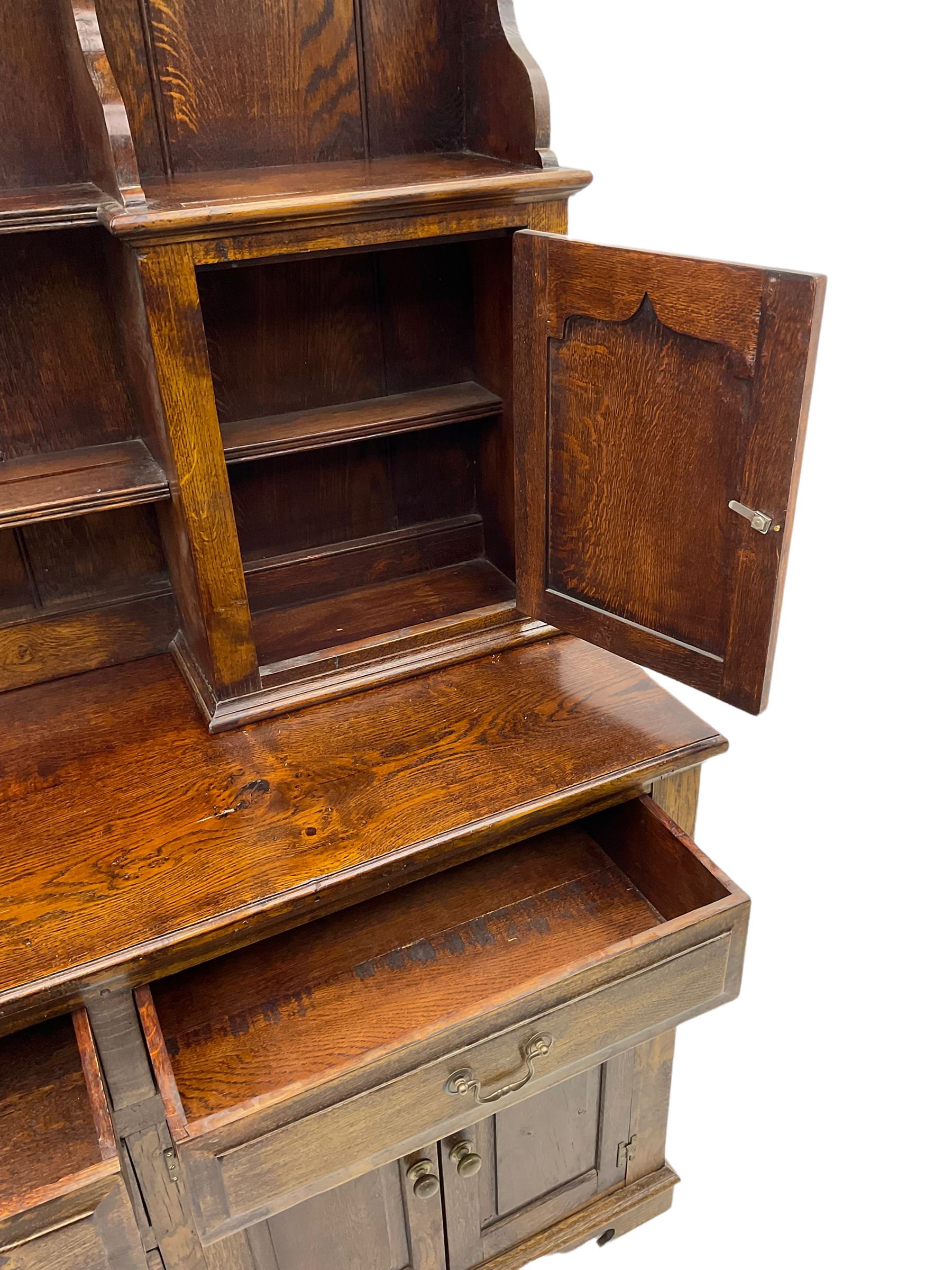 Traditional oak dresser, the moulded cornice over shaped apron, three heights plate rack fitted with two cupboards, the base fitted with six drawers and two double cupboards, panelled pointed ogee arched doors, on bracket feet