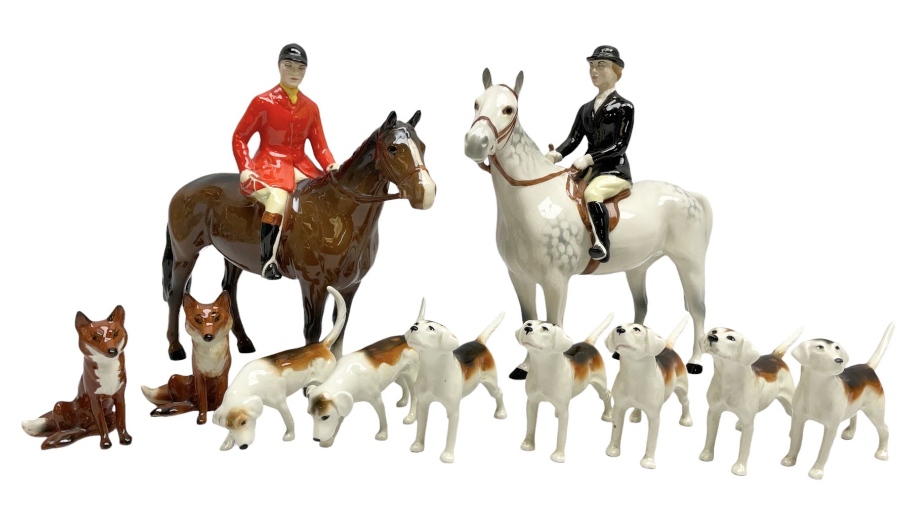 Beswick hunting group, comprising huntswoman on grey horse no 1730, huntsman on brown horse no 1501, two seated fox figures no 1748 and seven fox hounds, all with printed marks beneath (11)