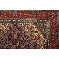 North West Persian Tabriz hand-knotted rug, ivory field with a central lozenge medallion in deep indigo and madder red, enclosing a inner reserve with stylized floral motifs, spandrels with angular floral sprays, main border of repeating floral vinery and palmettes, framed by multiple guard borders, with cotton fringe ends