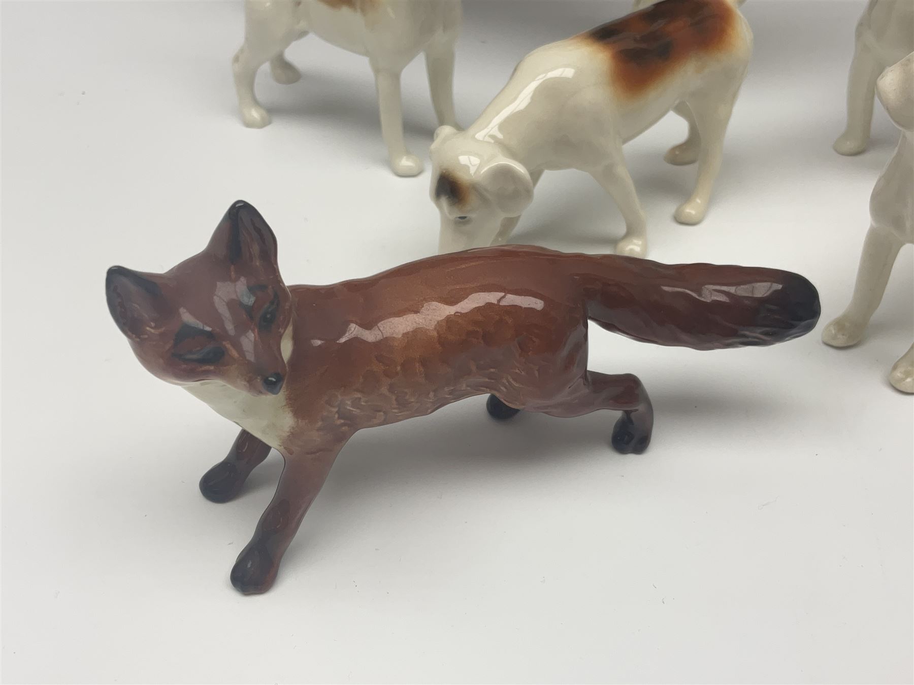 Beswick hunting group, comprising huntswoman on grey horse no 1730, huntsman on brown horse no 1501, fox figure no 1440 and eight fox hounds, all with printed marks beneath (11)