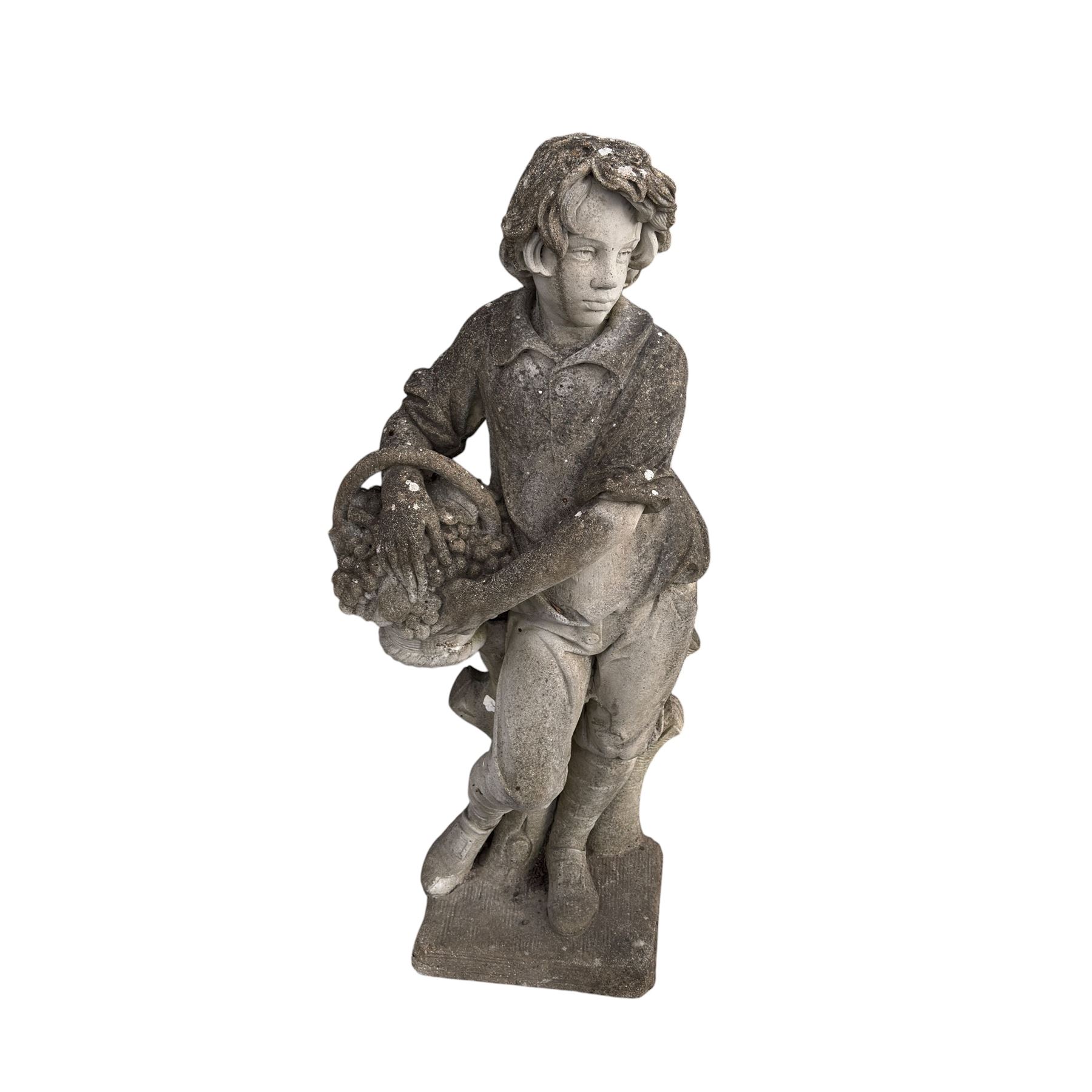 Haddonstone - weathered cast stone garden statue of a boy holding a basket of grapes, modelled with curled locks of hair wearing a tunic and breeches leaning against a naturalistic tree stump, on square base