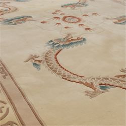 Late 20th century Chinese wool carpet, cream field with five stylized dragons arranged in a circular formation around a central flaming pearl motif, dragons depicted with elongated bodies and clawed feet amongst stylized cloud forms, enclosed within a narrow inner border and a wider outer border decorated with traditional Chinese motifs and symbols