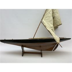 Pond yacht with part black painted mahogany hull and keel, working rudder and mast with three sails W90cm H95cm, loose mounted on mahogany stand
