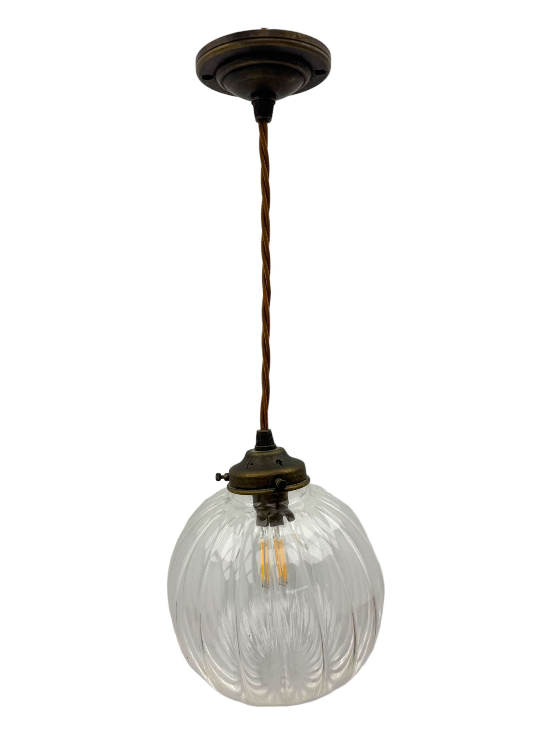 Set of two small and two large pendant lights, each with clear glass spherical shade with moulded swirl pattern, suspended from twisted cords, brass ceiling rose