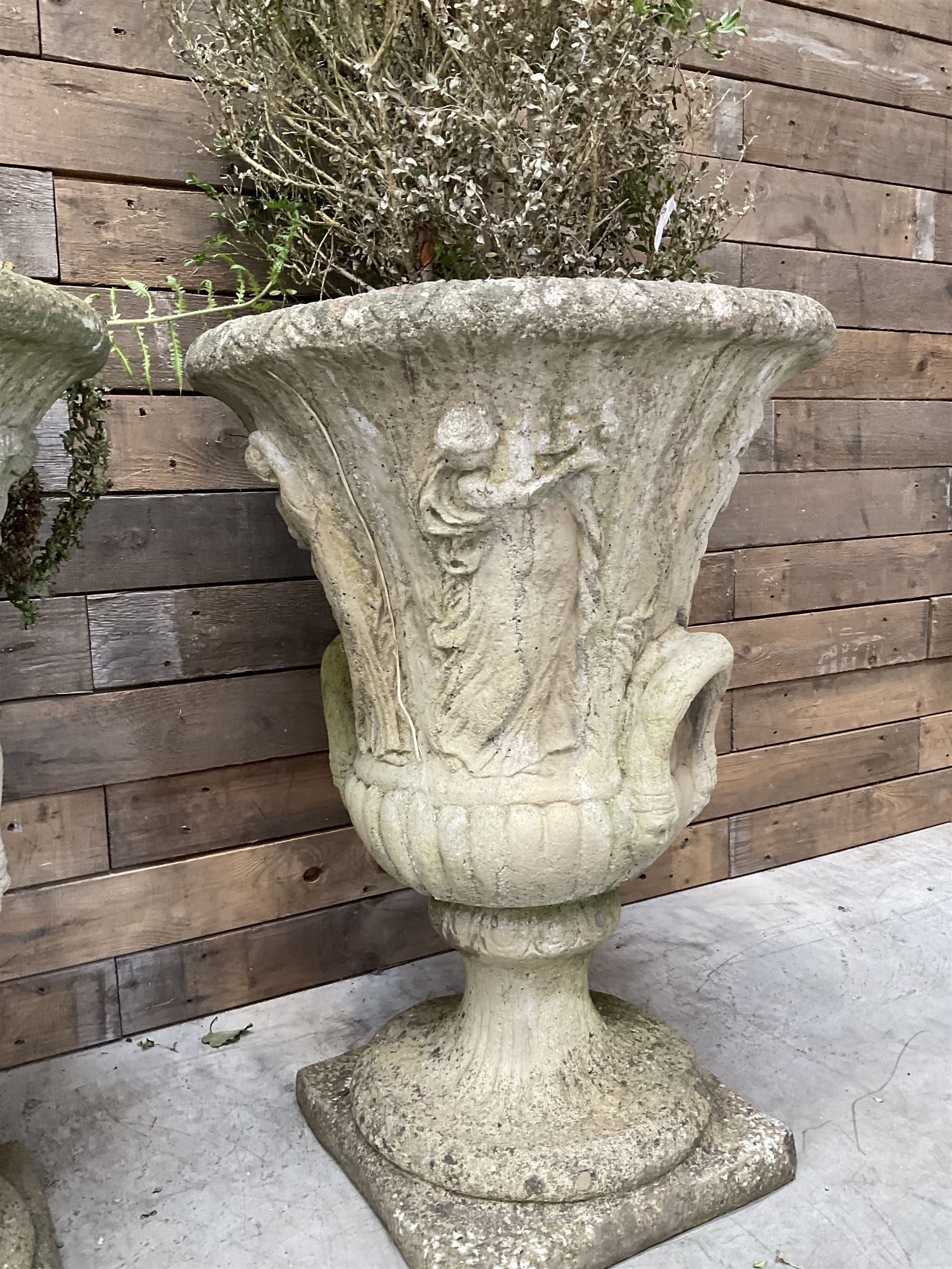 Set of four Victorian design cast stone Grecian urns, tapering form cast with figures and handles, square plinth bases