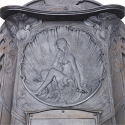 Art Nouveau cast iron fireplace, shaped hood with scrolling foliate crest, relief cast panel of female figure seated within shell form amidst wave motifs, uprights cast with foliate designs