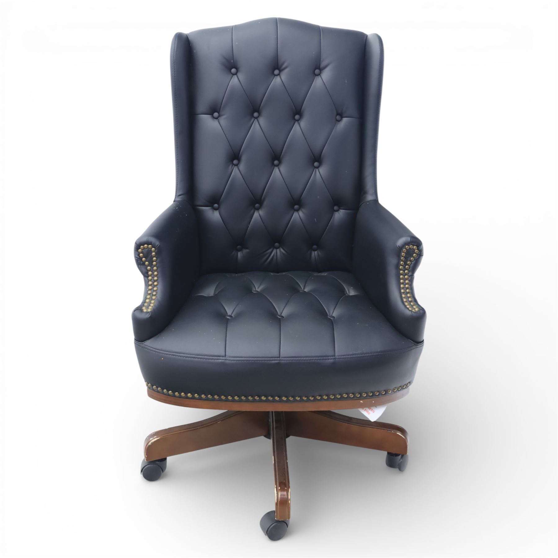 Chesterfield style desk chair upholstered in black, brass studded trim with tall button backed seat, with faux wooden base raised upon castors