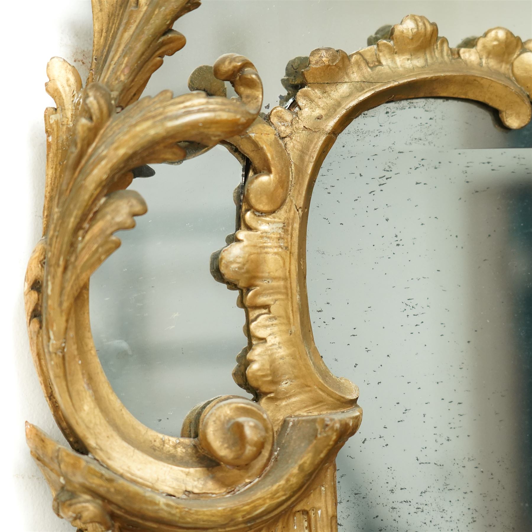 George III Chippendale design carved giltwood and gesso wall mirror, the impressive protruding pierced pediment decorated with flared acanthus leaves interspersed with flower heads and berries, over an arched outer-frame - the cresting comprised of C-scrolls carved with dripping icicle motifs, the uprights formed of scrolling acanthus with swags of grapevines and foliage, over a scrolled cartouche terminal, the inner-frame of architectural form with bell-flower details and a shaped cresting with scrolling acanthus leaves, all enclosing a central slightly bevelled rectangular mercury glass plate, surrounded by smaller plates