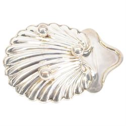 Edwardian silver shell butter dish, upon three bun feet, together with a matching shell spoon engraved with initial, both hallmarked Josiah Williams & Co, London 1906 and 1914, together with an Edwardian milk jug, open sucrier and sugar tongs, the jug and bowl of circular part fluted form with bead rim, hallmarked Mappin & Webb Ltd, Sheffield 1902, both sets contained within fitted tooled leather boxes with silk and velvet lined interiors