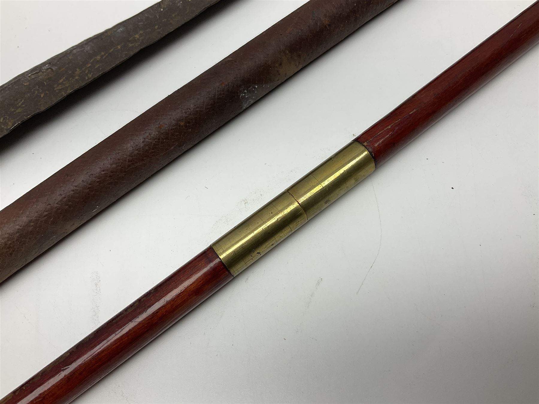 19th century continental folding knife with 15.5cm single edged blade, the pierced brass and iron handle with remains of horn grips L21.5cm overall closed; turned horn handled knife with foliate engraved blade; battlefield relic German 1884/98 knife bayonet; iron spear head; leather covered swagger stick; and two-piece gun cleaning rod