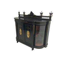 Victorian ebonised credenza side cabinet, raised balustrade back with urn finials and a central carved cartouche, carved and gilded with floral garland decoration, central doors with gilt panels painted with figures sitting over a lake enclosing two shelves, flanked by applied bellflower detail and glazed bow-front side doors, raised on ring turned feet with castors