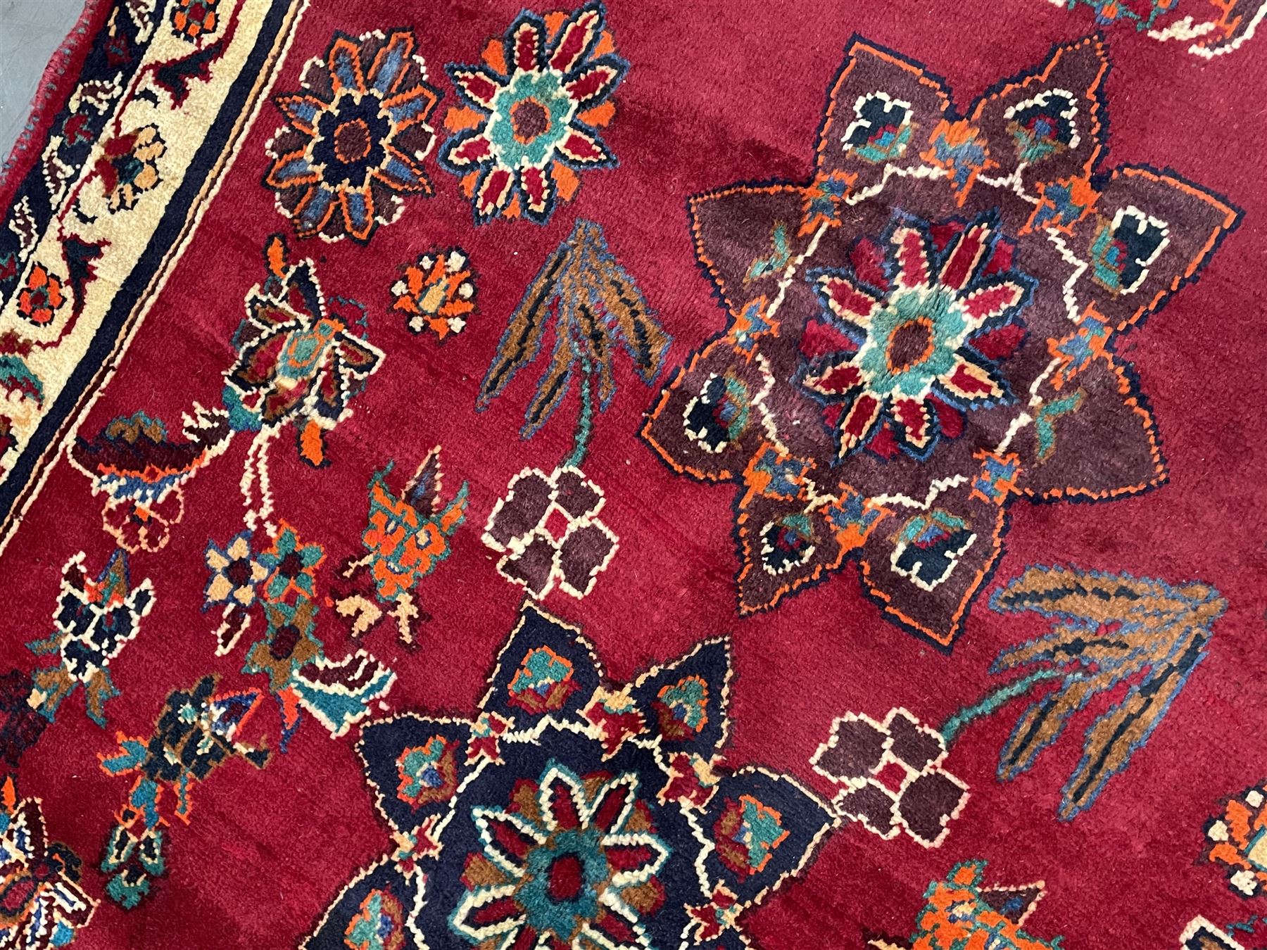 Persian rug, red ground field decorated with stylised flower heads and bird motifs, floral scrolling border