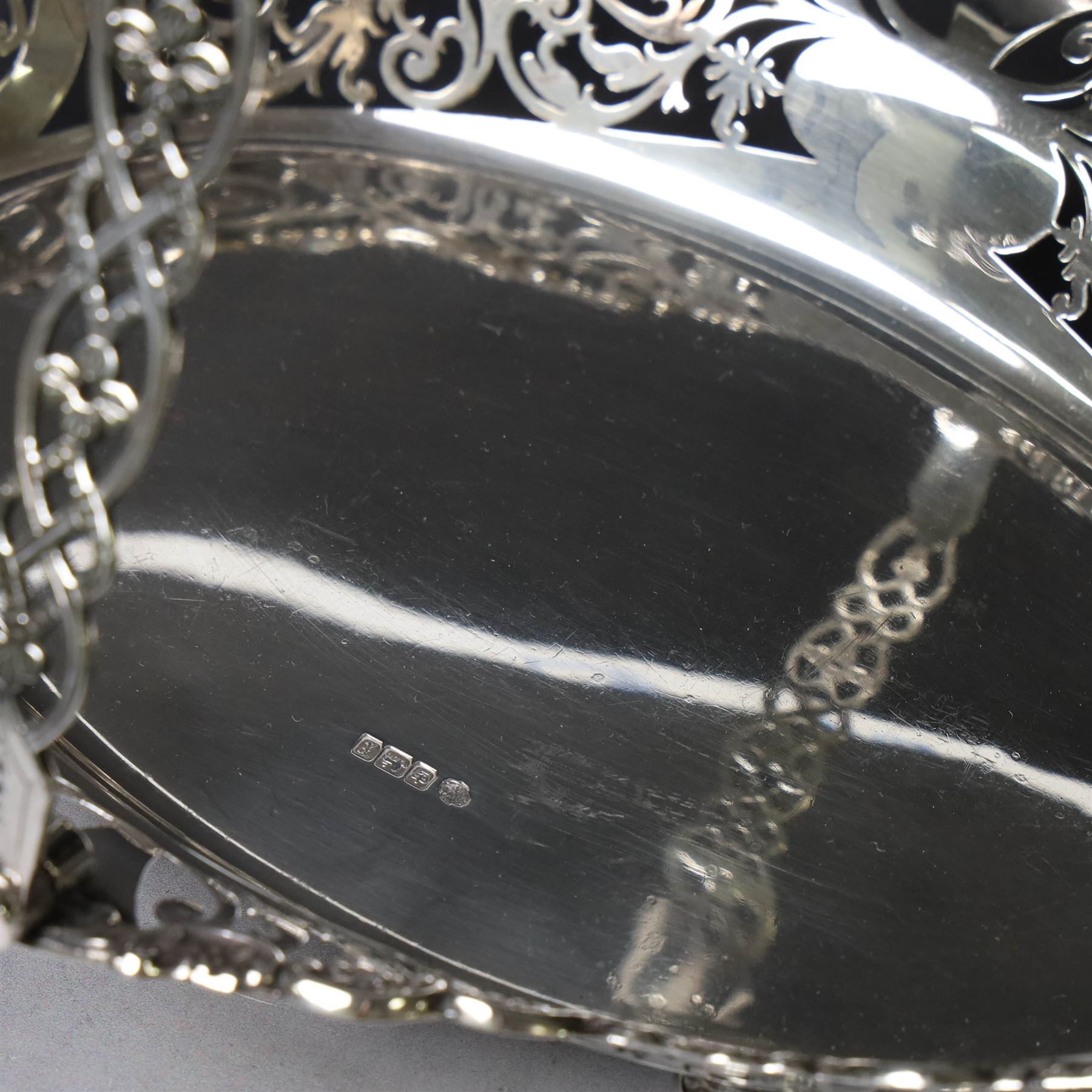 Early 20th century swing handled basket, of oval form with pierced sides and floral C scroll rim, upon four bun feet, hallmarked William Hutton & Sons Ltd, Sheffield 1915, widest point W29cm