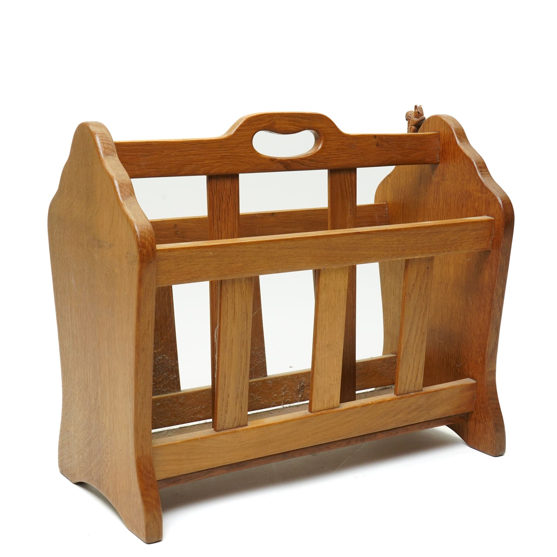 Squirrelman - oak magazine rack, the shaped ends enclosing a central slatted support with carrying aperture, enclosed by slatted sides and base, with carved squirrel signature, by Wilfrid Hutchinson of Husthwaite