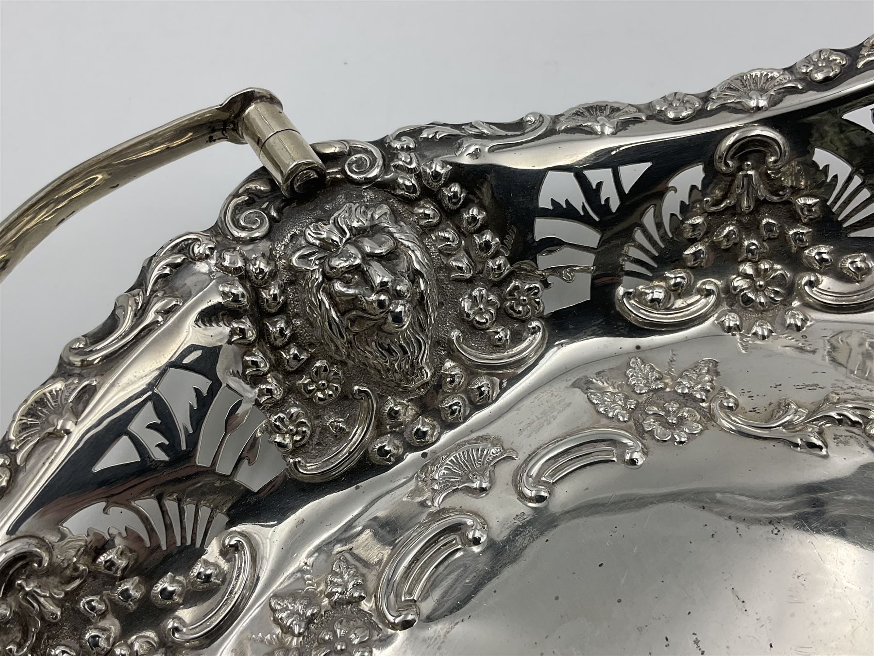 Edwardian silver swing handled basket, of navette form, with four repousse lion masks to each corner and with pierced and embossed floral, scroll and shell decoration to sides, base and handle, hallmarked Charles Horner, Birmingham 1906, height including handle H20cm