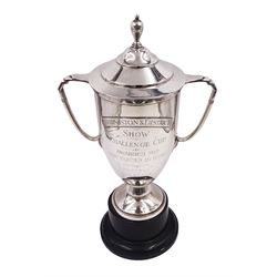 1930s silver trophy cup, with twin handles and stepped domed lid with silver finial, the body with presentation engraving 'Burniston & District Show Challenge Cup, Awarded for Best Hunter in Show, Reserve Champion' with winners engraved verso, hallmarked William Comyns, London 1935, upon black plastic base, with applied winners plaque, including base and lid H33.5cm