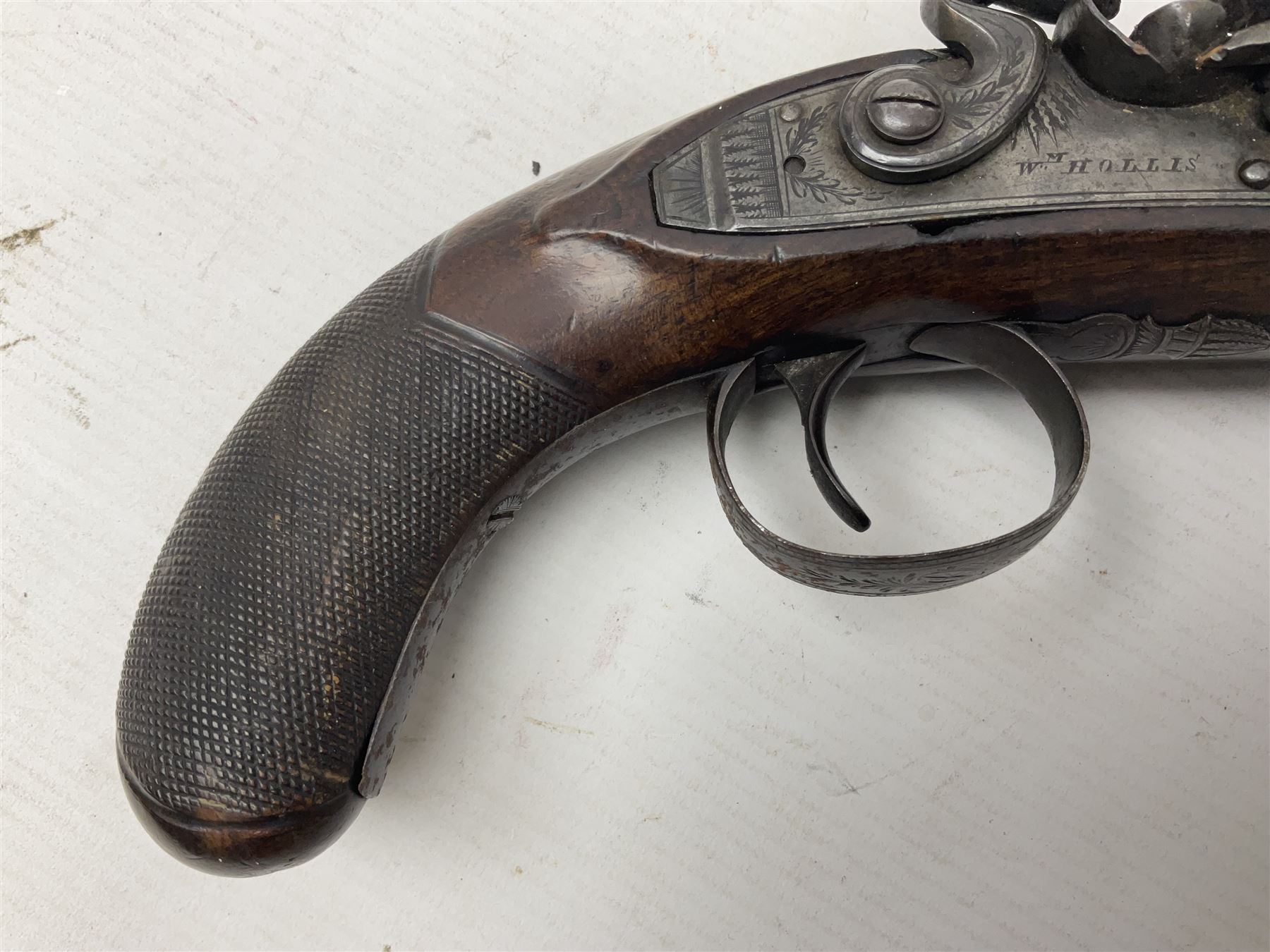 Early 19th century Wm. Hollis flintlock belt or pocket pistol, approximately 20 bore, the 10cm barrel with ram rod under, engraved lock plate with maker's name and roller frizzen, engraved trigger guard with pineapple finial and walnut stock with chequered grip L25cm overall