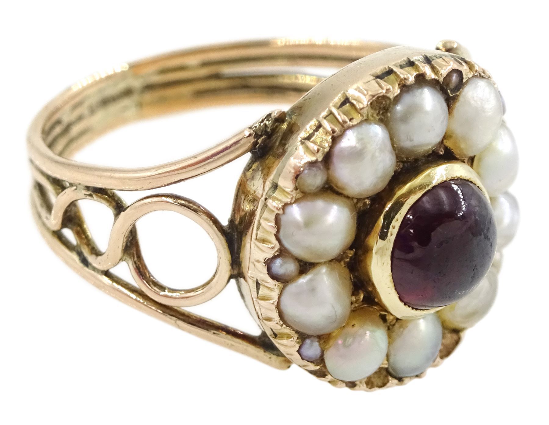 George III 9ct rose gold garnet and pearl mourning ring, single cabochon garnet, with split and seed pearl surround and pierced design shoulders, the back inscribed and dated 1808