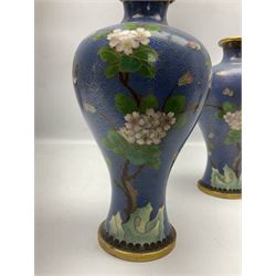 Pair of Chinese cloisonné vases decorated with birds and blossoming branches upon blue ground, H23cm