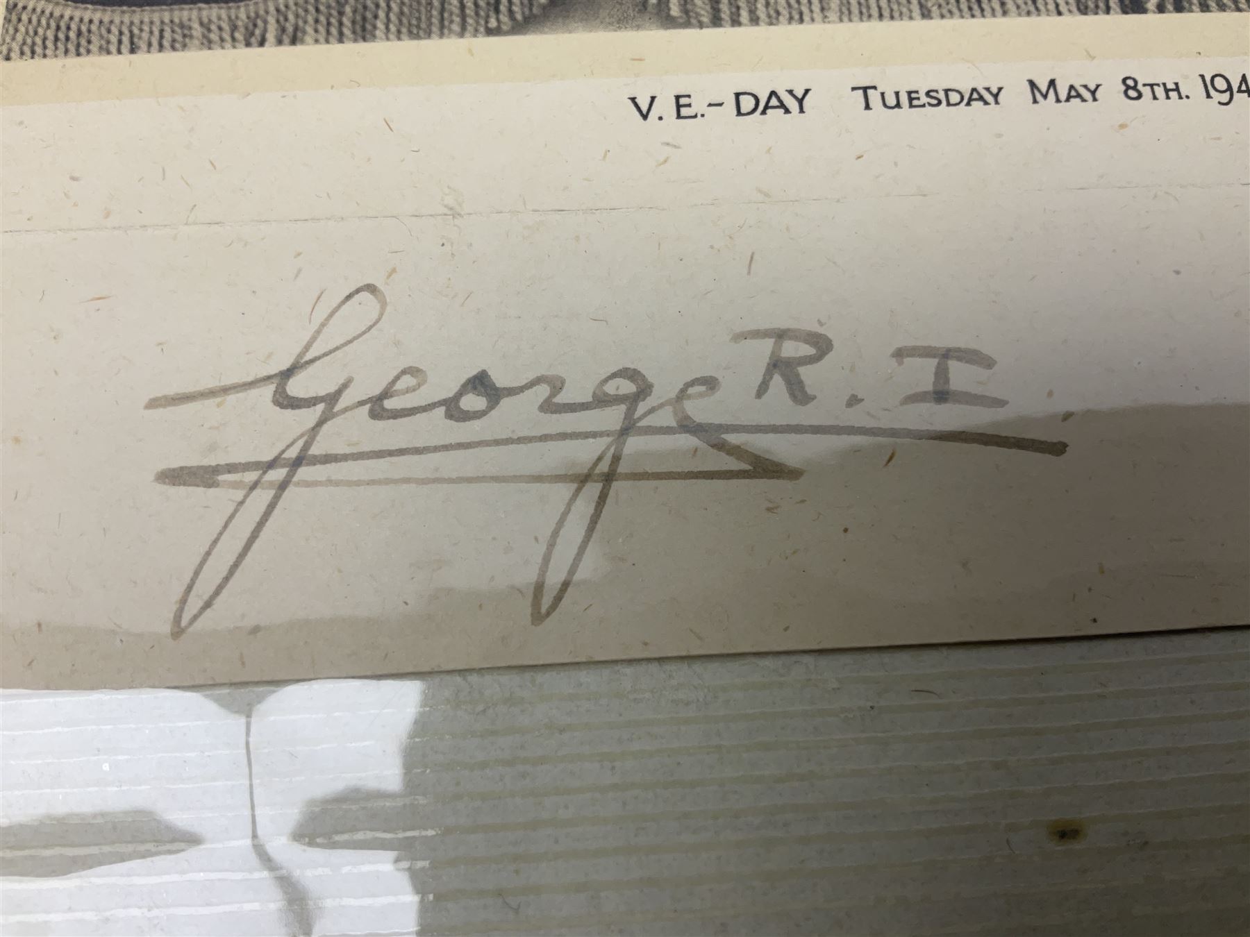 King George VI and Queen Elizabeth - the photograph and signatures only from a 1945 Christmas card depicting The Royal Family waving from the balcony of Buckingham Palace, on V-E Day Tuesday May 8th 1945, signed 'George R.I. Elizabeth R.'