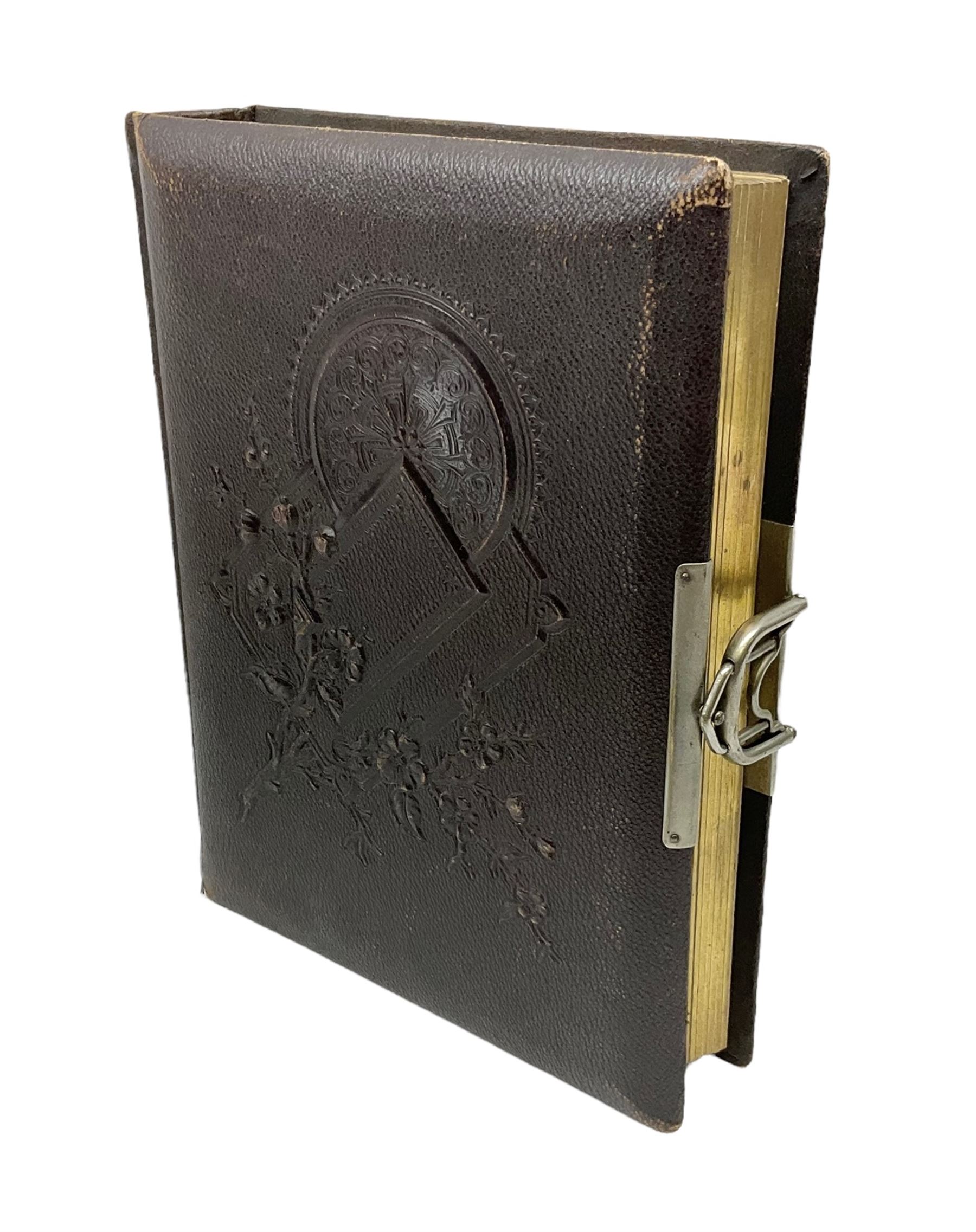 Victorian leather bound photo album, the interior leaves containing apertures of various sizes and shapes of portraits surrounded by printed floral designs, H28cm