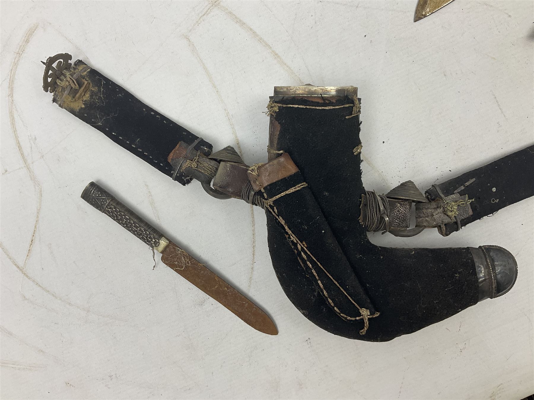 Omani Khanjar dagger, the 19cm curved blade with pronounced medial rib to either side, waisted hilt with dome shaped pommel and silver mounted horn grip decorated with an embossed band; in an intricately decorated silver scabbard with silver rings woven into the belt mount and fitted with original coin mounted silver thread-work belt with additional side knife in sheath verso L34cm overall, belt length 81cm; together with a Nepalese kukri in leather scabbard with one skinning knife (2)