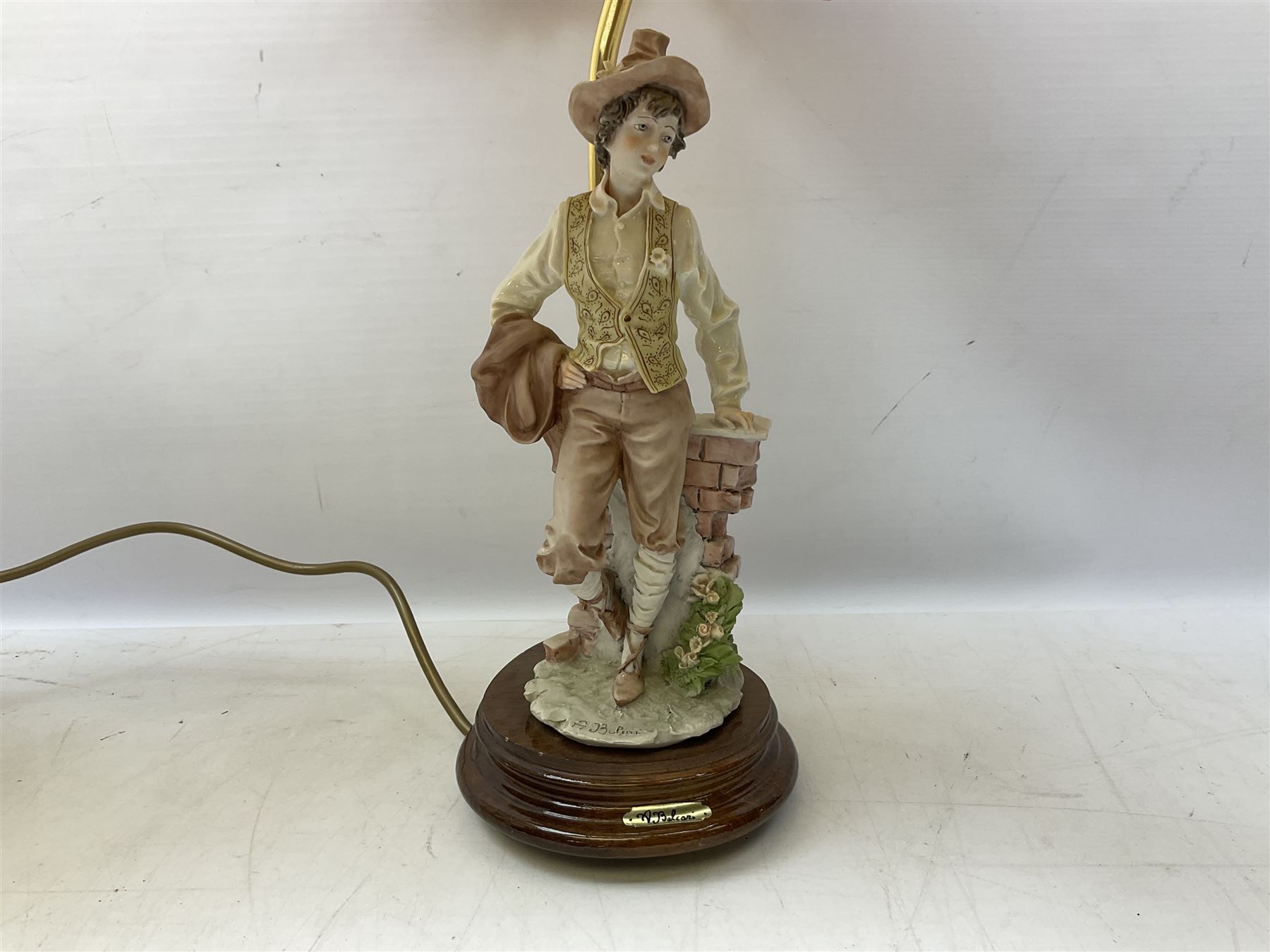 A Belcari figural table lamp, modelled as a young gent leaning upon brick wall, on turned wood base, signed, H70cm incl shade, together with bronzed figural table lamp of a lady with parasol upon ornate circular plinth base, two ceramic table lamps and another lamp (5)