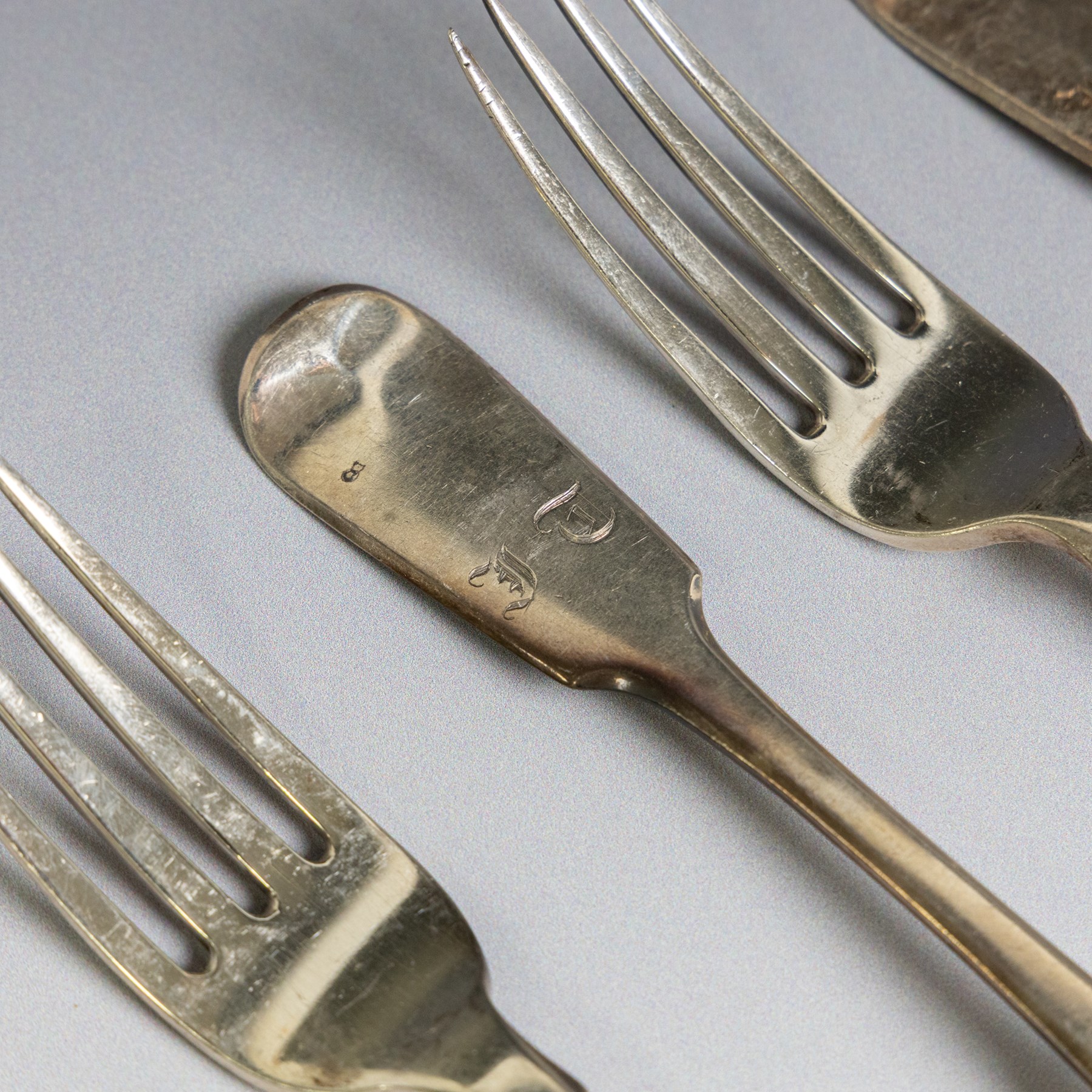 Seven silver Fiddle pattern table forks, comprisng set of four William IV examples, hallmarked William Eaton, London 1836, and three Victorian examples with engraved initials, hallmarked John Robert Harris, London 1846
