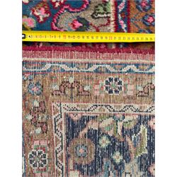 Pair of Persian wool rugs, each with rich red ground, one centred with a diamond-shaped medallion and navy spandrels within a floral field, the other with radiating floral medallion and scrolling foliate motifs, both enclosed by multiple borders with palmette and flowerhead designs, from the region of Kashan 291x376, 299 x 378 