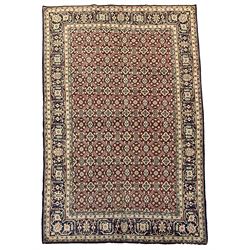 Persian red ground rug, the field decorated with repeating floral pattern, scrolling border with stylised plant motifs