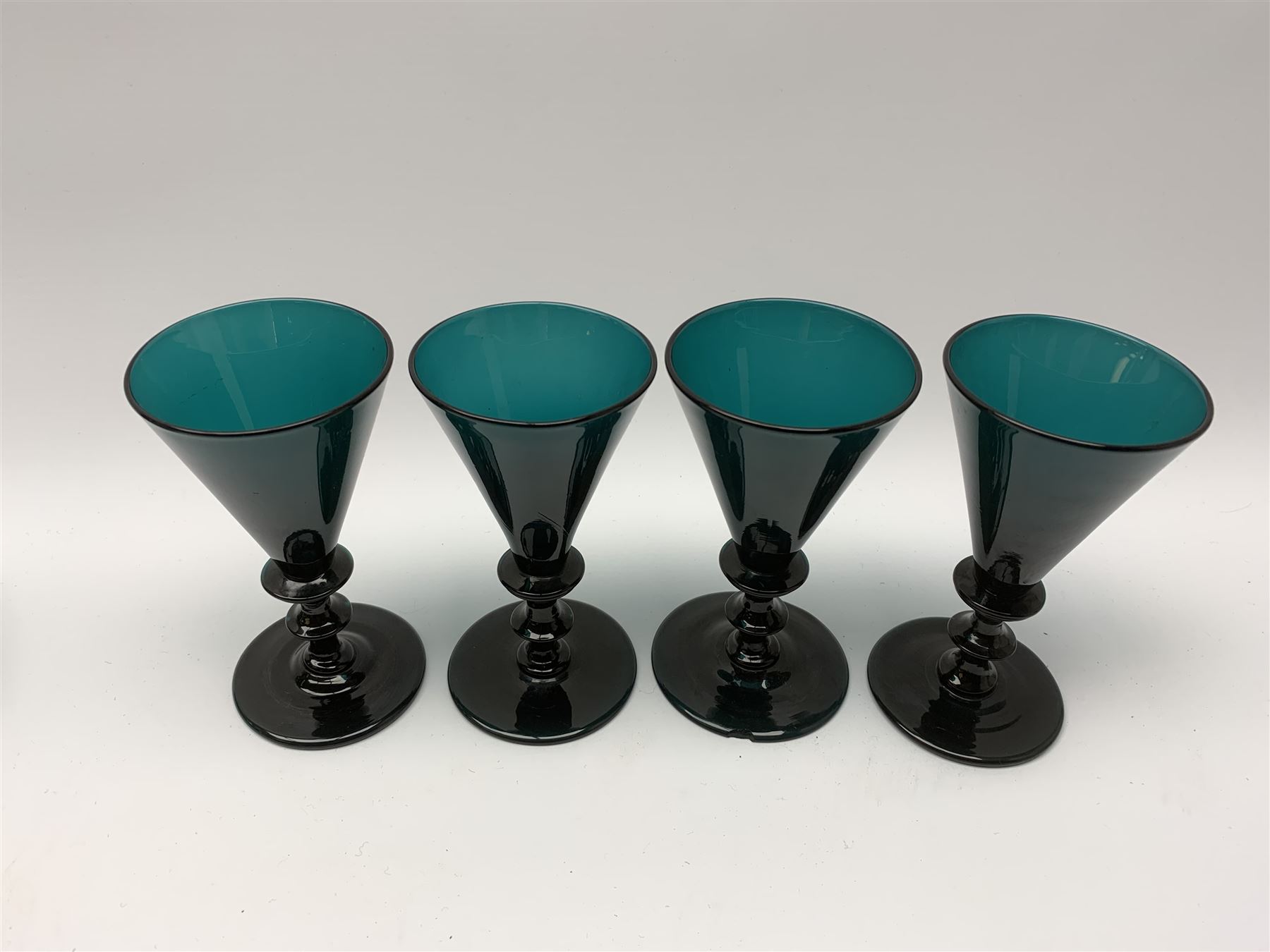 19th century green glass ships decanter with flat topped stopper, H21.5cm, together with a set of four 19th century green glass wine glasses, the funnel bowls upon bladed knopped stems and circular feet, H13cm