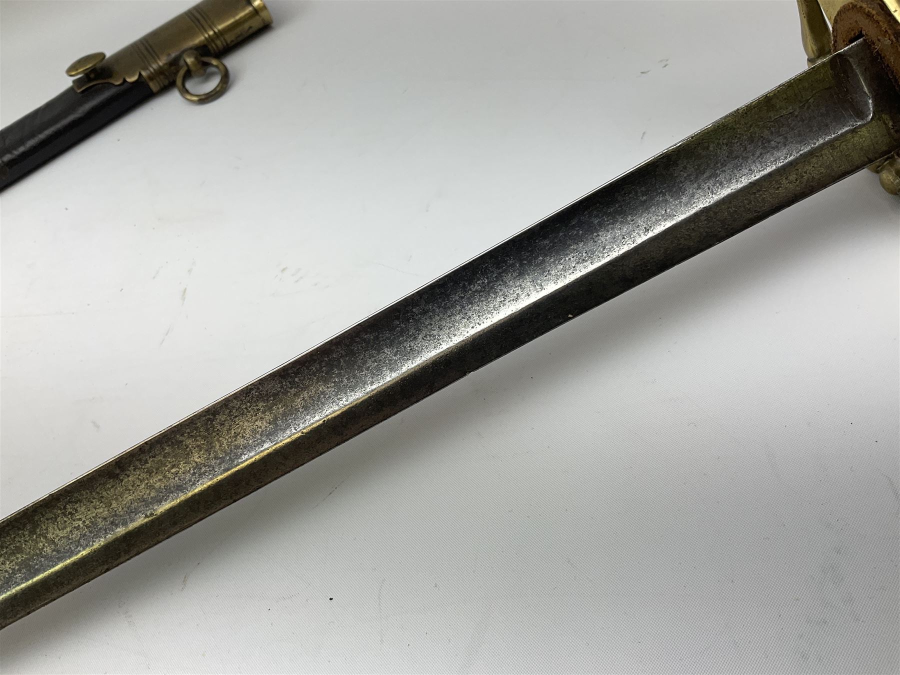 Five-ball spadroon sword with 78.5cm fullered steel blade and brass hilt with fluted swollen grip; in brass mounted leather scabbard, the locket with traces of the makers name John Knubley 11 Charing Cross L97.5cm overall