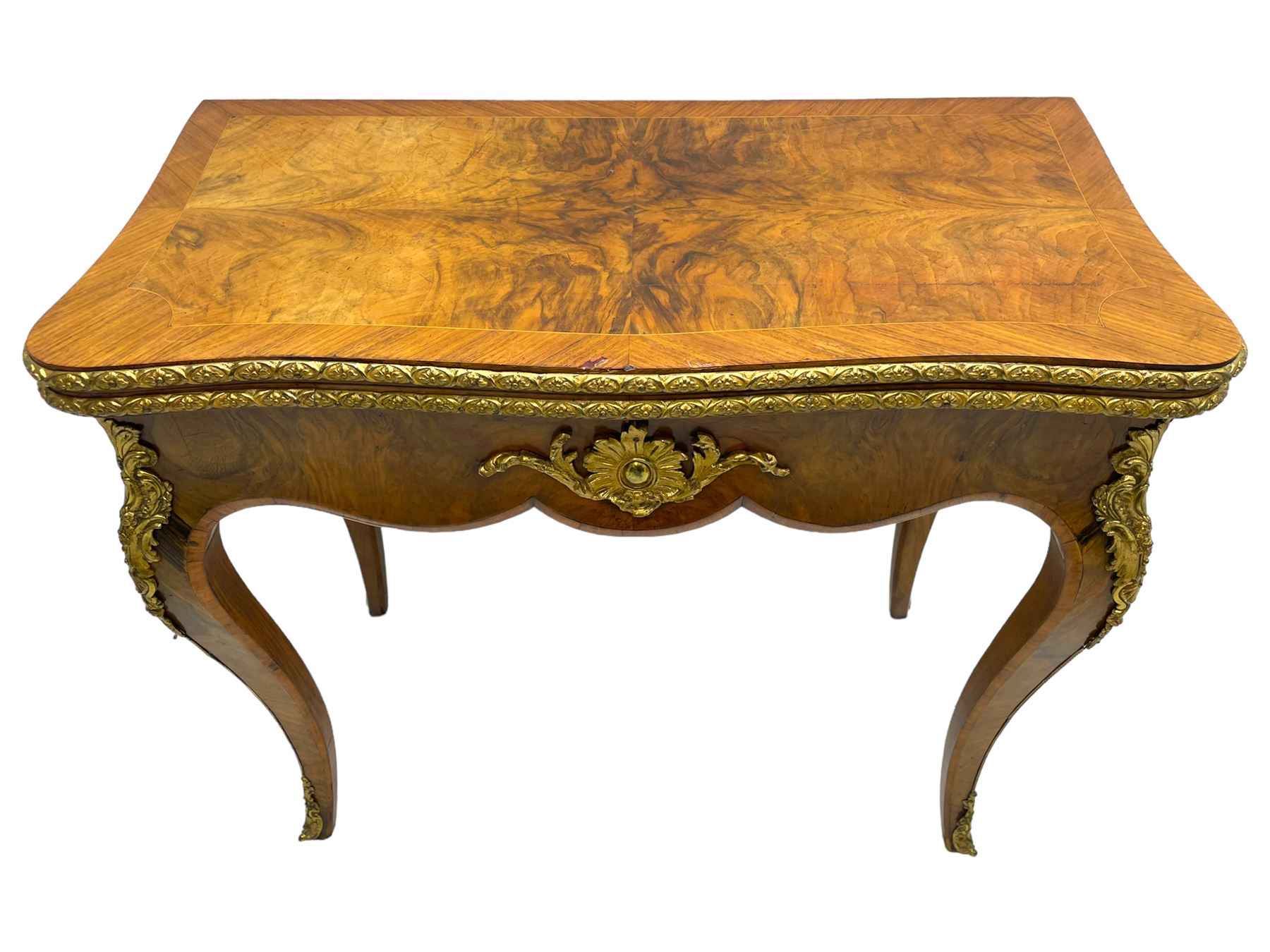 20th century French walnut and Kingwood card table, shaped fold-over top with figured quarter-matched veneers and floral egg and dart moulded edge in gilt metal, shaped aprons decorated with shell motifs with extending foliage, pull-out action base revealing storage well, on cabriole supports with ornate gilt metal mounts 