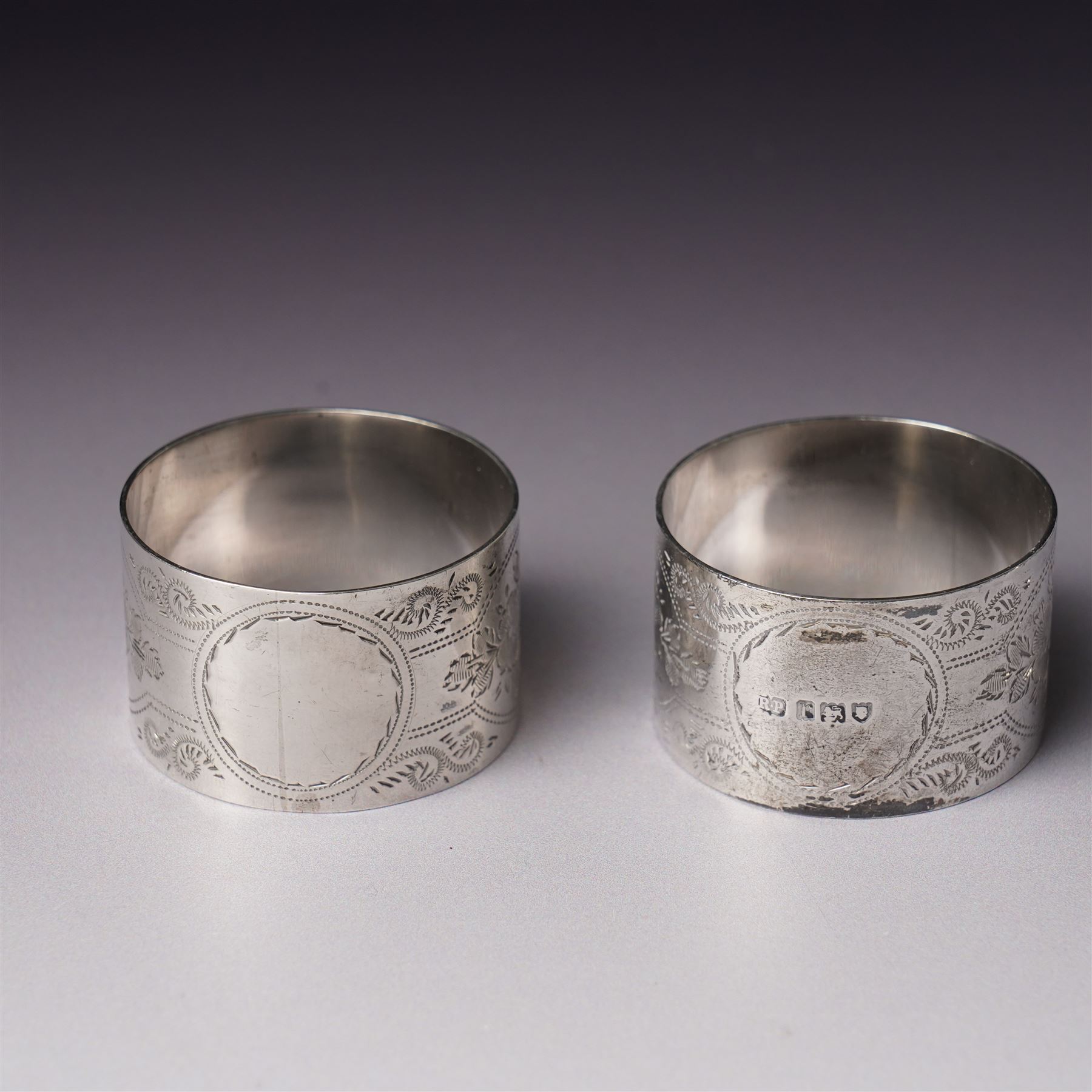 Pair of engraved silver napkin rings London 1912, two 19th century fiddle pattern dessert spoons, four condiment and teaspoons and a silver pepperette