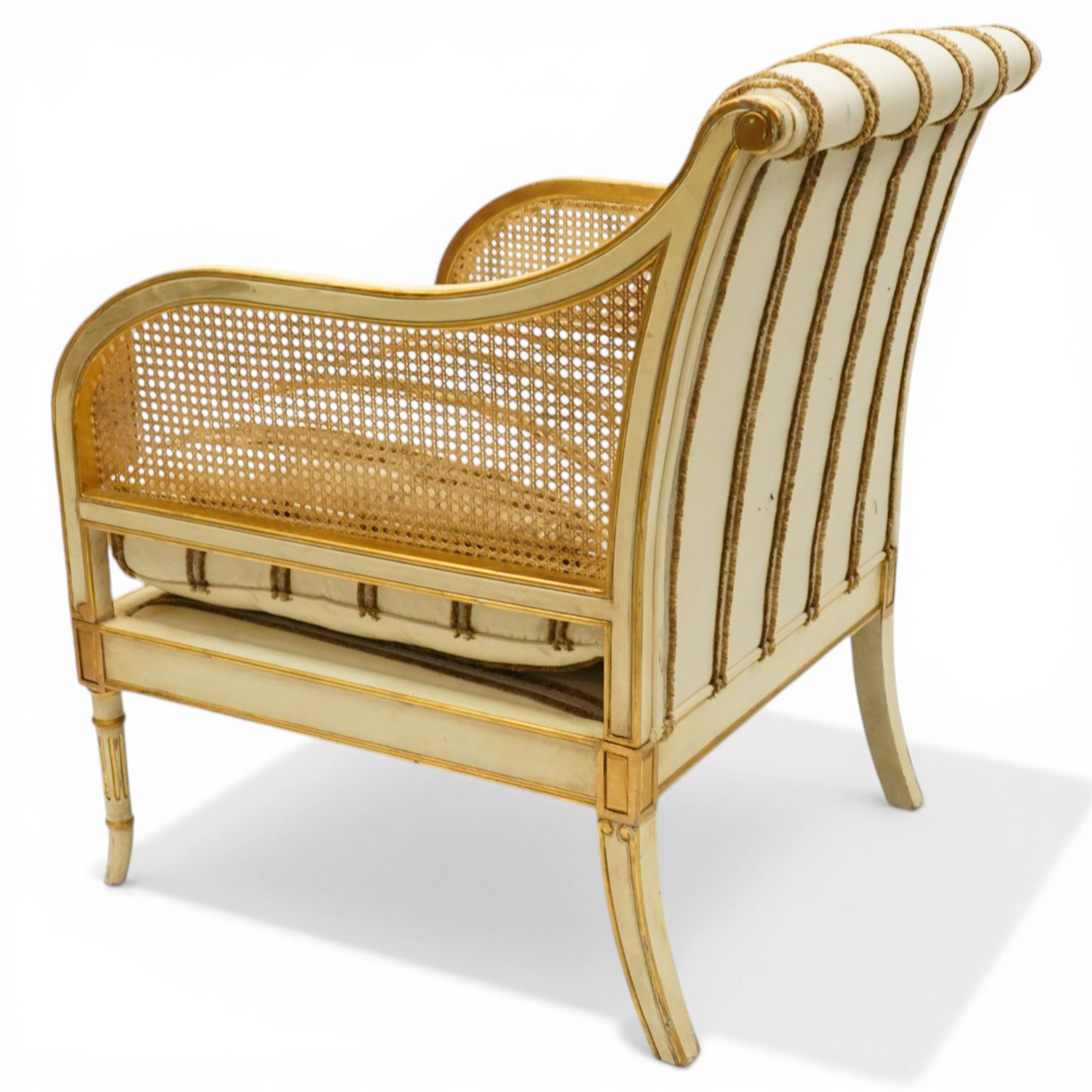 Louis XV design cream painted and parcel-gilt bergere armchair of large proportions, high scrolled back over canework arms, upholstered in striped fabric with over-stuffed loose seat cushion, on fluted supports