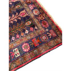 Kurdish red ground rug, decorated with plant motifs and stylised flower heads 