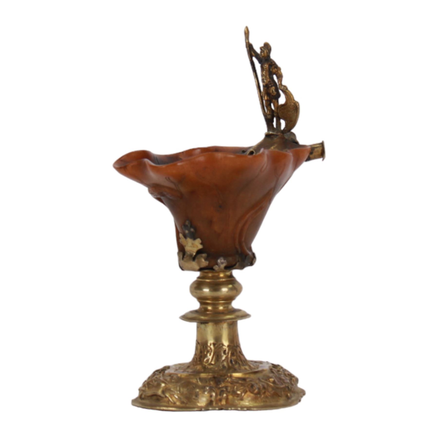 Rhinoceros horn libation cup with gilt metal mounts, probably 18th century, the cup of naturalistic form carved with veins, with gilt figural handle, upon a gilt knopped stem and quatrefoil base embossed and chased with trophies and foliate motifs, H14.5cm