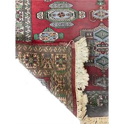 Persian red ground rug, the field decorated with triple stylised medallions and floral urn motifs, repeating border
