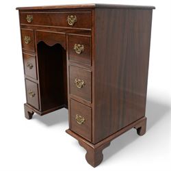 Georgian design mahogany kneehole desk, moulded rectangular top over single drawer, shaped frieze drawer and six short drawers, recessed kneehole with cupboard, on bracket feet