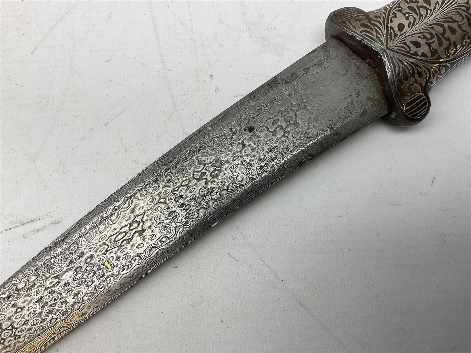 Indian Khanjar dagger with 28cm curving damascus steel blade inlaid with silver floral emblem, white metal and niello style grip in the form of a bird's head with pronounced beak and matching scabbard L44cm overall