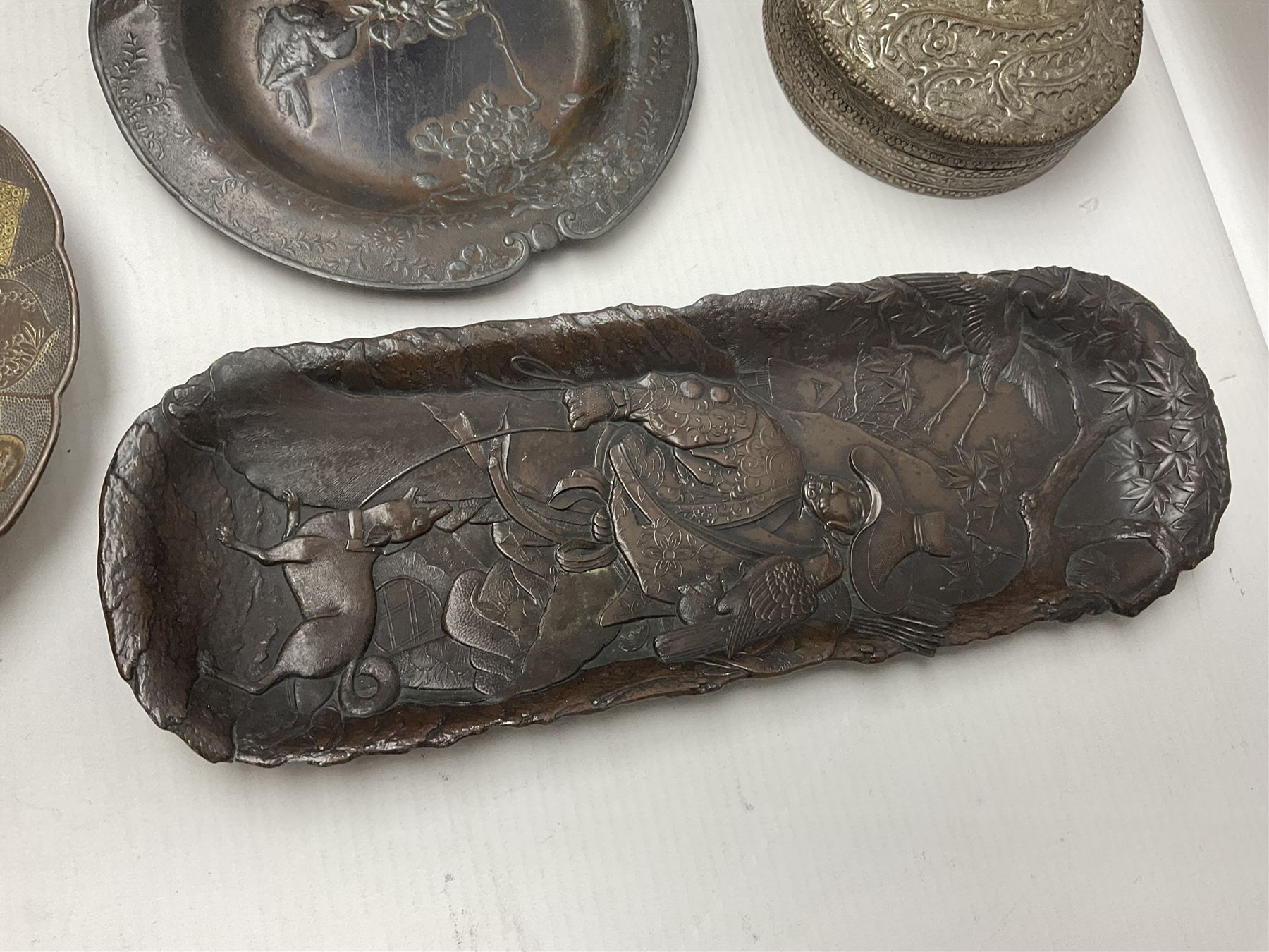 Brass sunfish ashtray, Chinese silver plated trinket box with mirror, bronzed matchbox cover and a collection of other Oriental bronzed embossed metal trays