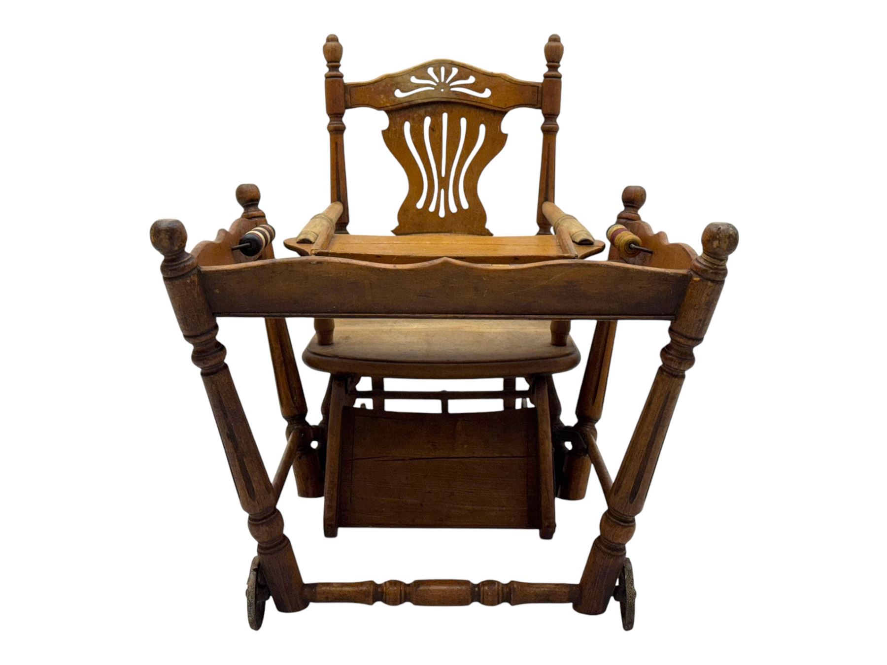 Late 19th century American oak child's metamorphic high chair and play table, carved spindle backrest with pierced splat, detachable tray with abacus and hand painted pastoral decoration, on turned supports with metal wheels