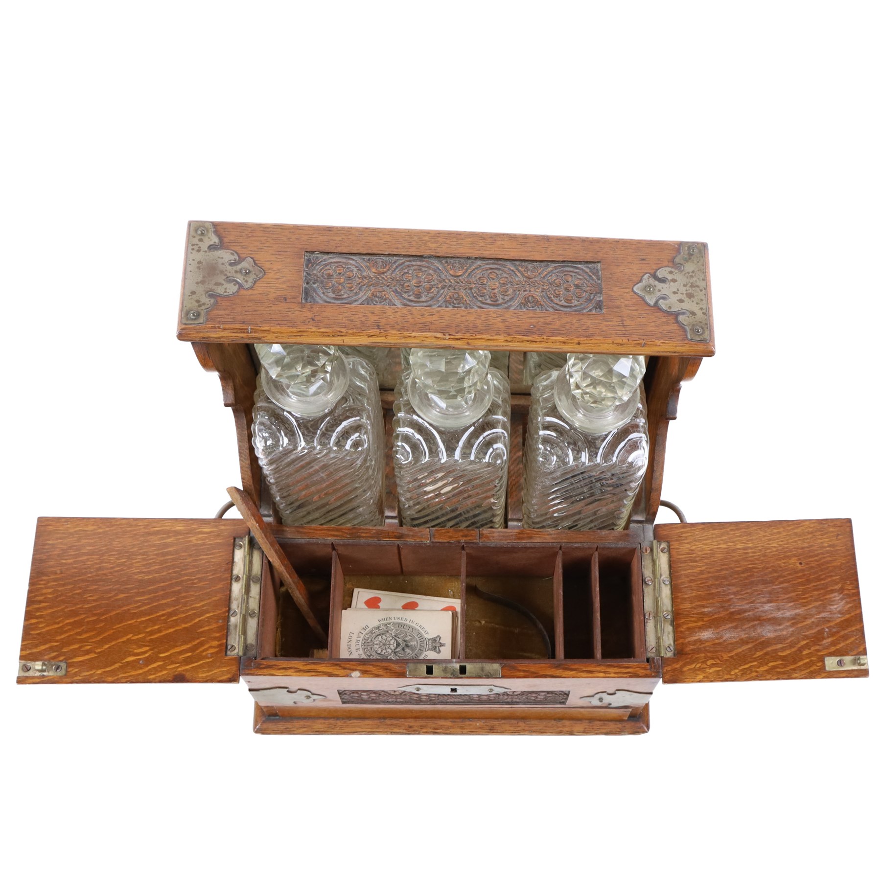 Victorian brass mounted oak tantalus, containing a set of three decanters, fitted with a games compendium to the front, H32cm