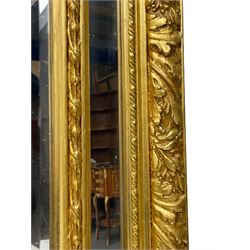 Large Italian Baroque design gilt wall mirror, the shell pediment over circular panel depicting classical female flute player with dancing putto within a tree landscape, the stepped arched upper frame surmounted by musical instrument playing putto and trailing flower heads, central bevelled mirror plate surrounded by plain segmented mirror plates, acanthus leaf moulded outer frame and foliate moulded inner slip