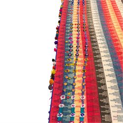 South West Persian Jajim kilim flatweave runner, woven in warp-faced flatweave and composed of narrow bands, striped field in various shades of rose, coral, ivory, indigo, turquoise, and olive, embellished along the sides with applied knotted wool rosettes and tassels, some missing (due to large size, the runner is illustrated in two sections)