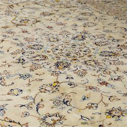 Central Persian Kashan hand-knotted carpet, ivory ground, with a central shaped floral medallion with pendants, surrounded by scrolling foliate and floral motifs incorporating rosettes, palmettes and delicate vine work, enclosed by a conforming ivory border with repeating palmettes and meandering vines, flanked by floral guard stripes, with cotton fringes