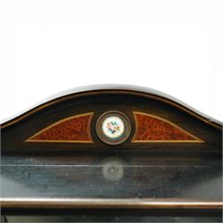Victorian Aesthetic Movement amboyna and ebonised cabinet, the arched raised back inlaid with amboyna and floral porcelain plaque, over a raised shelf with fluted and turned supports, and a bevelled mirror plate with brass beading beneath, the inverted-breakfront top over an ornate frieze drawer with guilloche style gilt-metal mounts and porcelain plaques, the panelled door with a central porcelain plaque depicting a lady in a fuchsia gown within concentric ebonised and amboyna inlays, flanked by architectural style uprights with Corinthian capitals, raised on turned feet